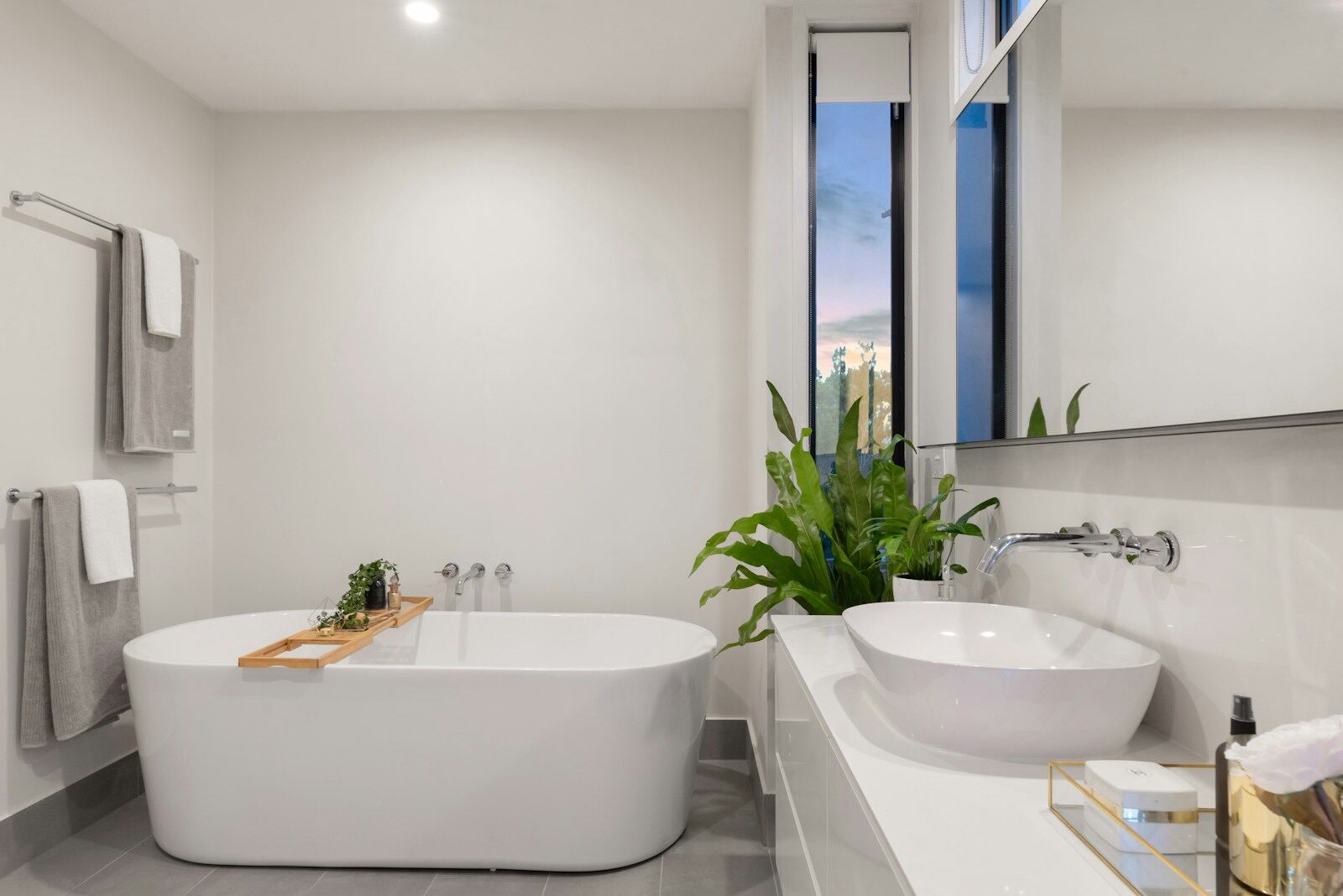 A clean bathroom with a freestanding tub, basin, and mirror